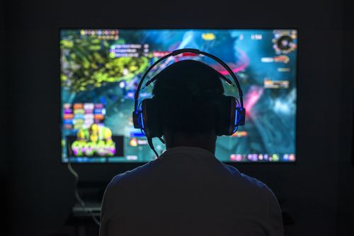 Boy playing games with headphones on in the dark